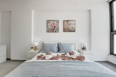 a white bedroom with a large bed with two teddy bears on it at Carisa Elysium Larnaca in Larnaka