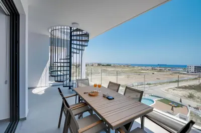 a dining room with a table and a view of the ocean at Carisa Elysium Larnaca in Larnaka