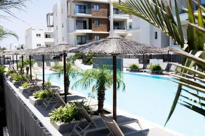 a hotel with a swimming pool with chairs and umbrellas at Cosmos Residence C102 in Paralimni