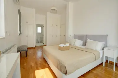 a white bedroom with a large bed and a chair at Villa Emilia in Ayia Napa