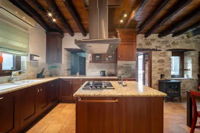 a large kitchen with wooden cabinets and a stove at Casa Piedra, Hidden Gem, Jacuzzi, BBQ, Patio in Monagroulli in Monagrulli