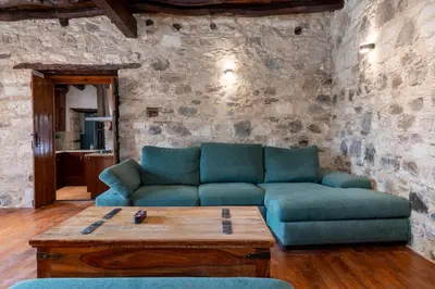 a living room with a blue couch and a wooden table at Casa Piedra, Hidden Gem, Jacuzzi, BBQ, Patio in Monagroulli in Monagrulli