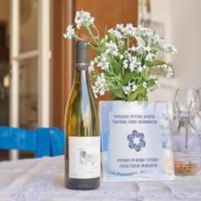 a bottle of wine sitting on a table with a vase of flowers at Lefkara View in Pano Lefkara