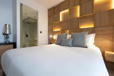 a bedroom with a large white bed and wooden wall at Old Port Hotel in Limassol