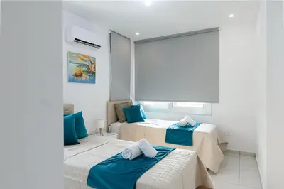 a bedroom with two beds with blue pillows on them at Dahlia Napa Villa in Ayia Napa