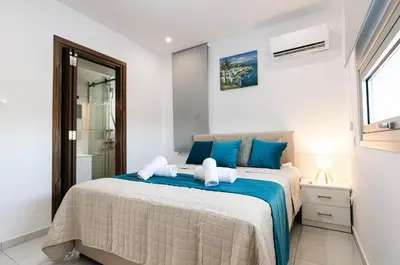 a bedroom with a large bed with blue pillows at Dahlia Napa Villa in Ayia Napa