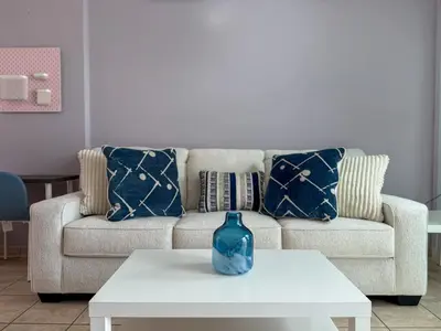 a couch with pillows and a vase on a coffee table at Zima Cove Calm Coastal Oasis in Limassol