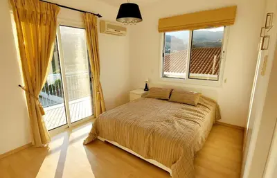a bedroom with a bed and two large windows at Villa Rossa in Pissouri