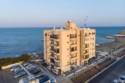 an apartment building next to a parking lot with cars at Lazuli Skyline & Sea View Penthouse in Larnaka