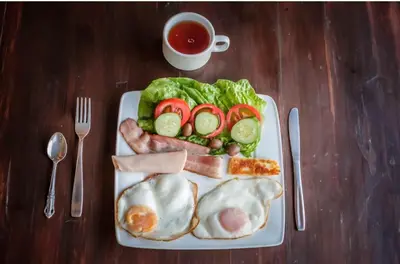 a plate of food with eggs and vegetables and a cup of tea at Domes at the Beach in Maroni