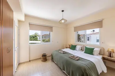 a bedroom with a large bed and two windows at Villa Chrystalla in Paralimni
