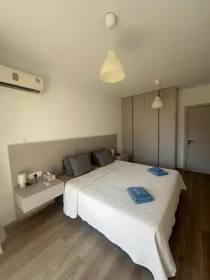 a bedroom with a large white bed with blue towels on it at Finikoudes Central Apartment in Larnaka