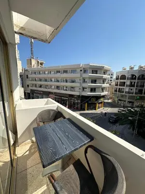 a table and chairs on a balcony with a building at Finikoudes Central Apartment in Larnaka