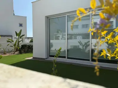 a house with windows and a yard with grass at TooCoool Villa - Elite Sea Breeze in Ayia Napa
