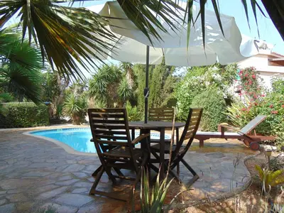 a table and chairs with an umbrella next to a pool at Konnos Villa in Protaras