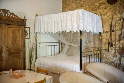 a bedroom with a canopy bed and a table with chairs at Maison Des Vignes Lofou in Lofou