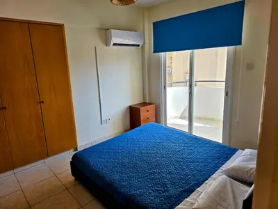 a bedroom with a blue bed and a window at Niki's Coastal Escape in Larnaka