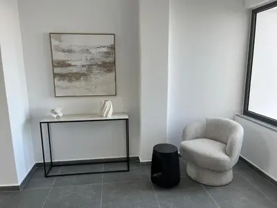 a living room with a chair and a table at Larnaca Elysium Seaside & Pool Retreat in Livadhia