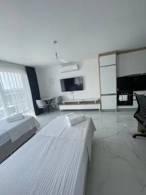 a white room with two beds and a tv at Four seasons sitesi in Aglantzia