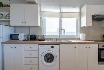 a kitchen with white cabinets and a washer and sink at The Seven - One Bedroom Apartment in Paralimni