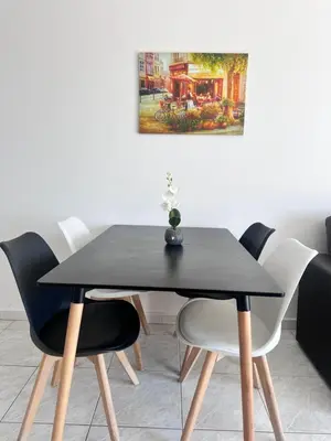 a black dining table and chairs with a painting on the wall at Near Makenzie Beach 51 in Larnaka