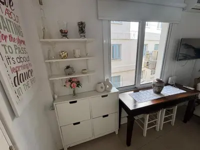 a room with a table and a dresser and a window at Modern 2BR Apartment 70m from Finikoudes beach in Larnaka