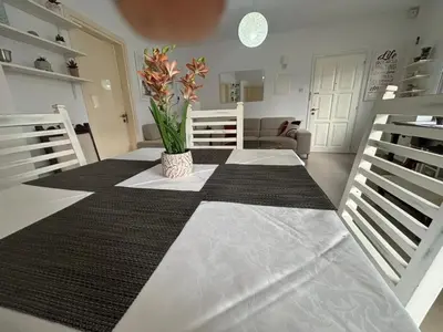 a room with a table with a vase of flowers on it at Modern 2BR Apartment 70m from Finikoudes beach in Larnaka