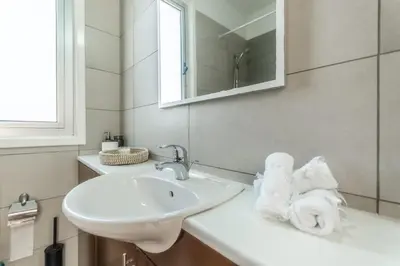 a white bathroom with a sink and a mirror at Black Swan Villa in Pervolia