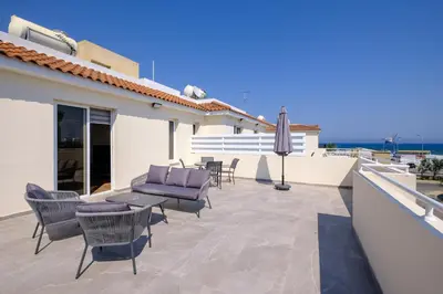 a patio with chairs and a table and an umbrella at Nautical Club Penthouse Apartments in Larnaka