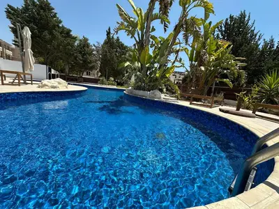 a large blue swimming pool with chairs and trees at Majestic Gardens 10 minutes from Larnaka Airport in Tersephanou