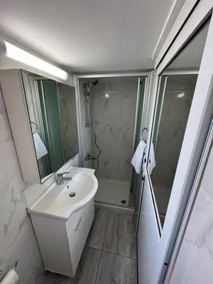 a white bathroom with a sink and a shower at Уютные Апартаменты с Балконом in Limassol