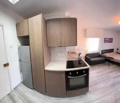 a kitchen with wooden cabinets and a refrigerator at Уютные Апартаменты с Балконом in Limassol