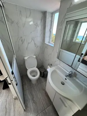 a white bathroom with a toilet and a sink at Уютные Апартаменты с Балконом in Limassol