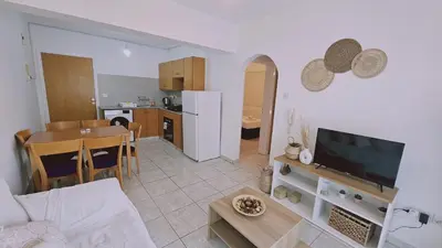 a living room with a couch and a table and a kitchen at STAY Miracle Apartment in Larnaka