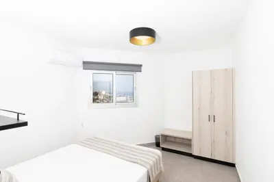 a white bedroom with a bed and a window at Napa Heights in Ayia Napa