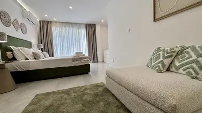 a bedroom with a bed and a couch and a window at Kantara Garden Apt by TrulyCyprus in Limassol