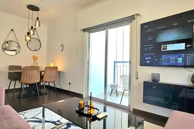 a living room with a large tv and a dining room at Central Park Suave 2 Bed in Limassol