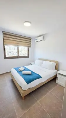 a bedroom with a large bed with a blue blanket at Olive Dunes Stay in Larnaka