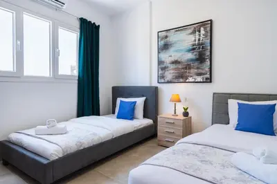 two beds in a room with two windows at Invictus 2-Bedroom Apartment in Larnaka