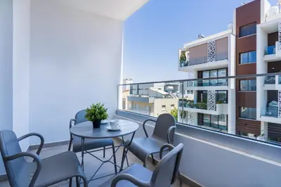 a balcony with a table and chairs and a building at Invictus 2-Bedroom Apartment in Larnaka