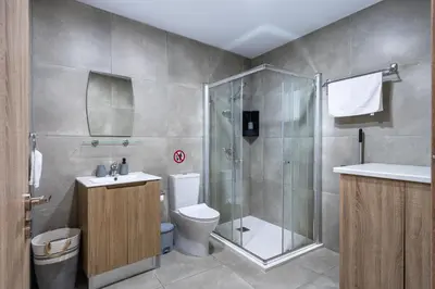 a bathroom with a shower and a toilet and a sink at Invictus 2-Bedroom Apartment in Larnaka