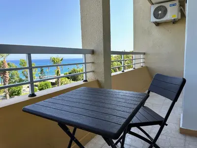 a black table and a chair on a balcony at Seaview Apartment in Limassol in Limassol