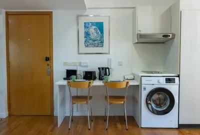 a kitchen with a washing machine and two chairs at Cosy & Bright European Uni Apt in Strovolos