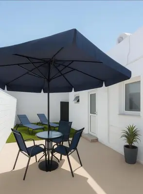 a table and chairs under a blue umbrella on a patio at Nissi Pearl Seaside Residence in Ayia Napa