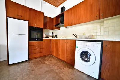 a white washer and dryer in a kitchen with wooden cabinets at Laouri Traditional 1-Bedroom in Kalopanayiotis in Kalopanayiotis