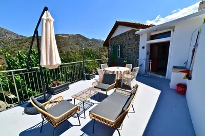 a patio with chairs and a table and an umbrella at Laouri Traditional 2-Bedroom in Kalopanayiotis in Kalopanayiotis