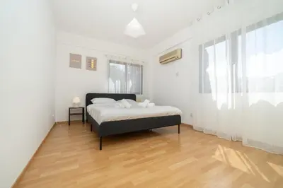 a white bedroom with a bed and a window at 2 bedroom flat in city centre in Nicosia