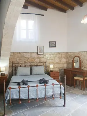 a bedroom with a bed with a stone wall at Traditional Cozy Retreat in Skarinou