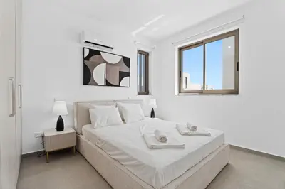 a white bedroom with a large bed and a window at St Nicholas Luxury 3-Bed Villa in Paralimni