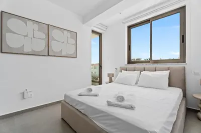 a white bedroom with a large bed with towels on it at St Nicholas Luxury 3-Bed Villa in Paralimni